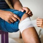 Someone gets their leg wrapped with gauze just below the knee