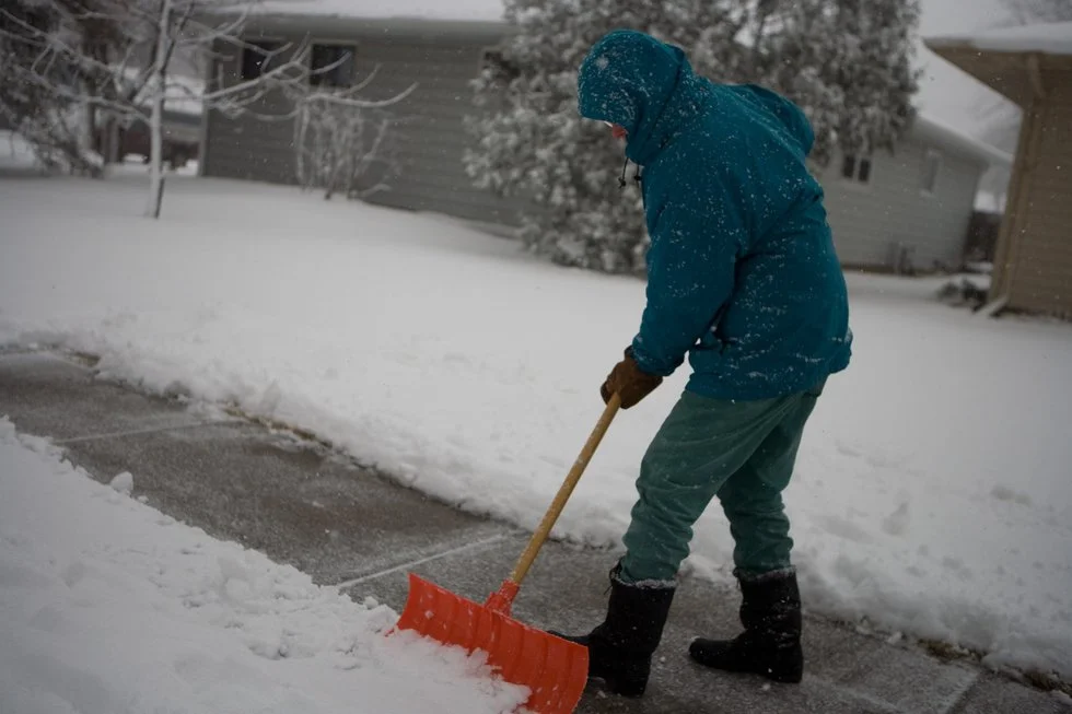 Person shovels snow off of sidewalk
