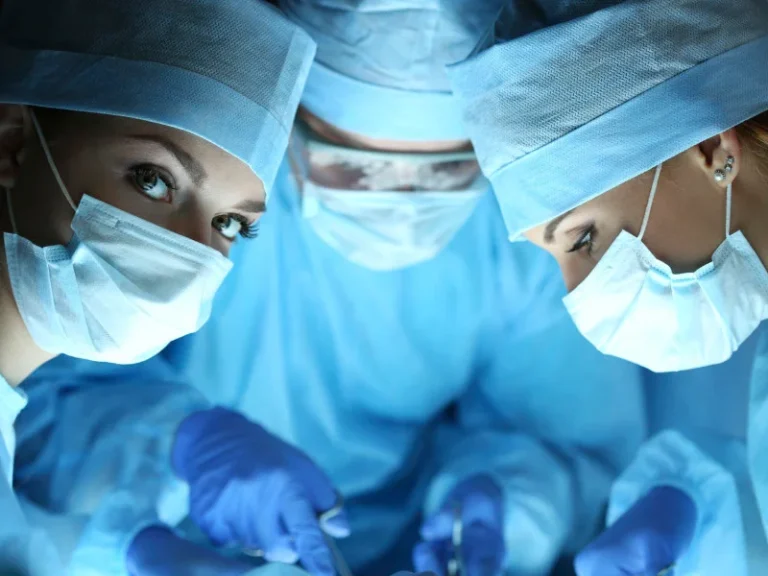 3 surgeons with masks and gloves operate together