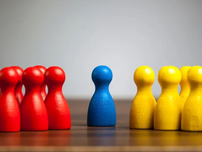 groups of red and yellow board game pawns sit on either side of a single blue pawn