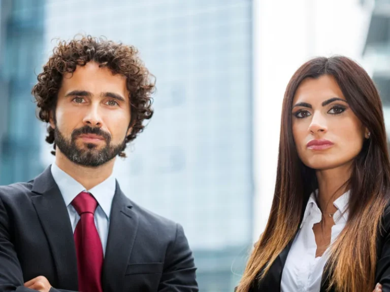 A man and woman with serious faces in suits