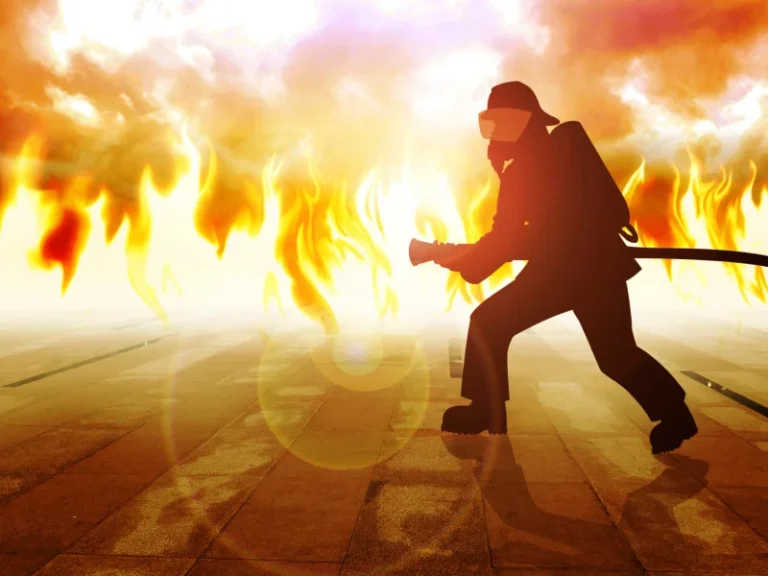 firefighter actively fights a fire in front of a big flame