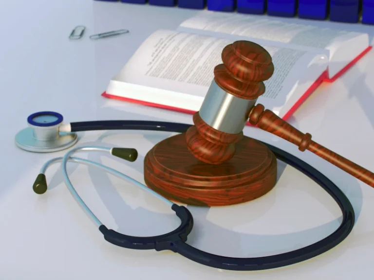 A stethoscope, a gavel, a book, and some paperclips lay on a table together
