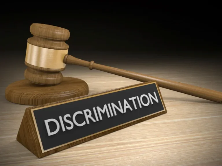 A gavel sits behind a desk sign that reads "discrimination"