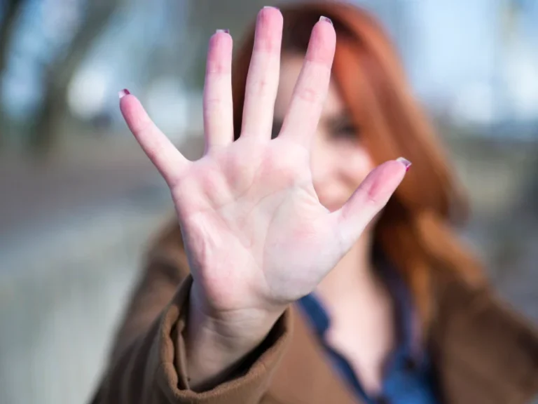 Woman holder her hand up covering her face, arm fully extended